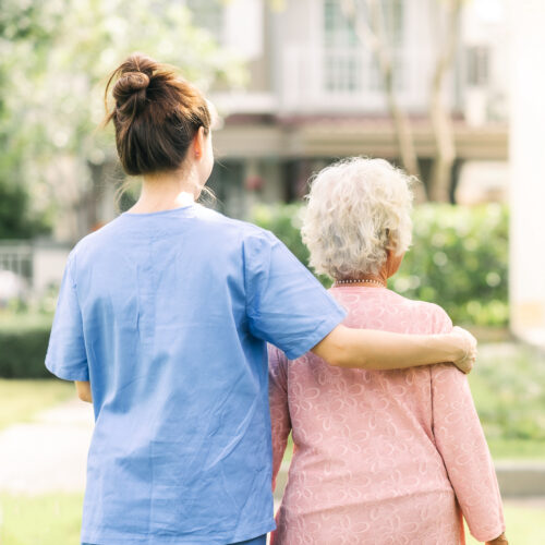 Nurse caregiver support walking with elderly woman outdoor